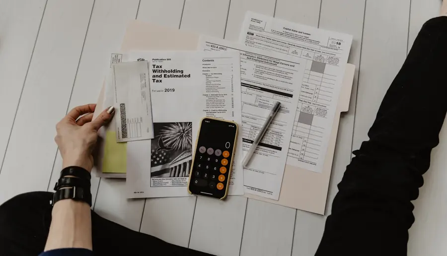 Tax and financial statements beside a calculator during statement preparation