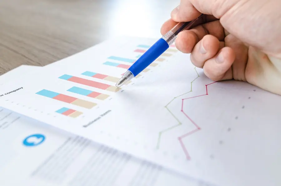 Analyst reviewing printed financial model charts with a pen
