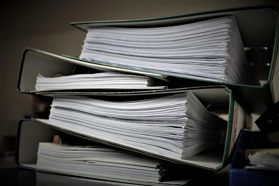 Stacked binders of unreconciled paperwork awaiting a bookkeeping cleanup