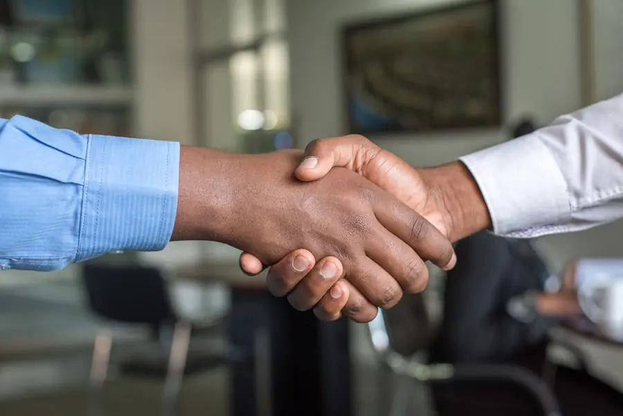 A firm handshake between business partners across a meeting table
